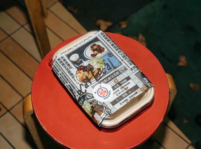 新村站著吃聯名外帶餐盒： 具有街頭報刊風格包裝的聯名外帶盒，方便消費者前往公園野餐分享。